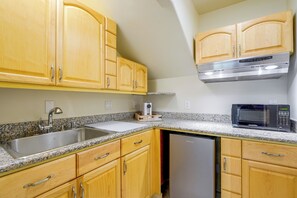 A kitchen with wooden cabinets, a stainless steel sink, a microwave, and a dishwasher.