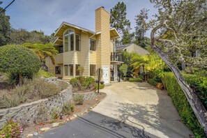 A two-story house with a chimney, large windows, and a stone pathway leading to the entrance.