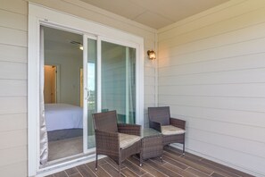 A room with a bed, a glass door leading to a balcony, and two wicker chairs. - Houston Home w/ Private Garage & Office Space (Houston)