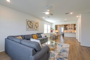 A modern living room with a gray sofa, a glass coffee table, and abstract wall art. - Houston Home w/ Private Garage & Office Space (Houston)