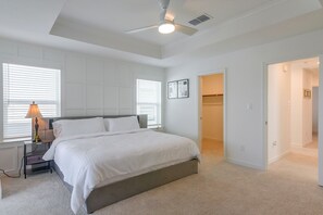 A bedroom with a bed, a nightstand, a lamp, a ceiling fan, and a door leading to another room. - Houston Home w/ Private Garage & Office Space (Houston)
