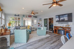 Ein geräumiges Wohnzimmer mit Deckenventilator, Fernseher und Kamin.