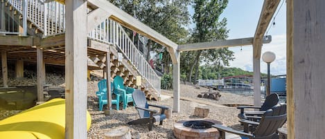 A wooden deck with a slide, outdoor seating, and a fire pit.