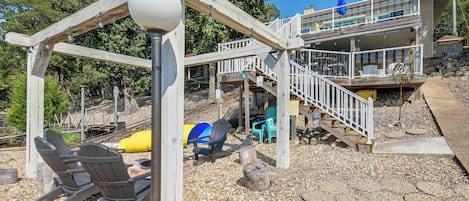 A wooden deck with a gazebo, outdoor seating, and a staircase leading to a building.