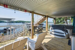 Een overdekt terras met buitenmeubilair, een trap en uitzicht op het water.
