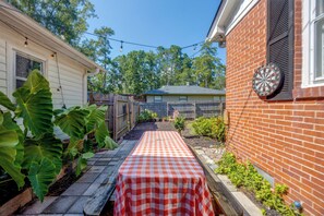 A backyard with a checkered table, a dartboard, and a wooden fence.