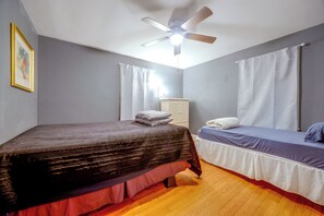 A bedroom with two beds, a ceiling fan, and a wardrobe.