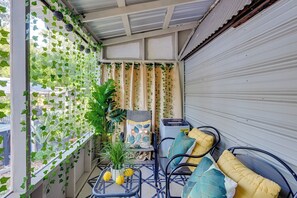 A balcony with a view of the street, covered with a metal roof, featuring a table with lemons, a potted plant, and a chair with cushions. - Private Patio & Grill! Tampa Studio Retreat (Tampa)