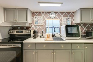 A kitchen with a stove, coffee maker, and a microwave. - Private Patio & Grill! Tampa Studio Retreat (Tampa)