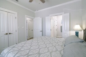 Une chambre à coucher avec un grand lit, deux portes, une table de chevet et une lampe.