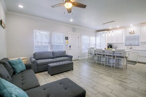 A modern living room with a grey sofa, ottoman, and a ceiling fan. - Private Dock, Pool Access:  Oceanfront Cottage (Port Isabel)