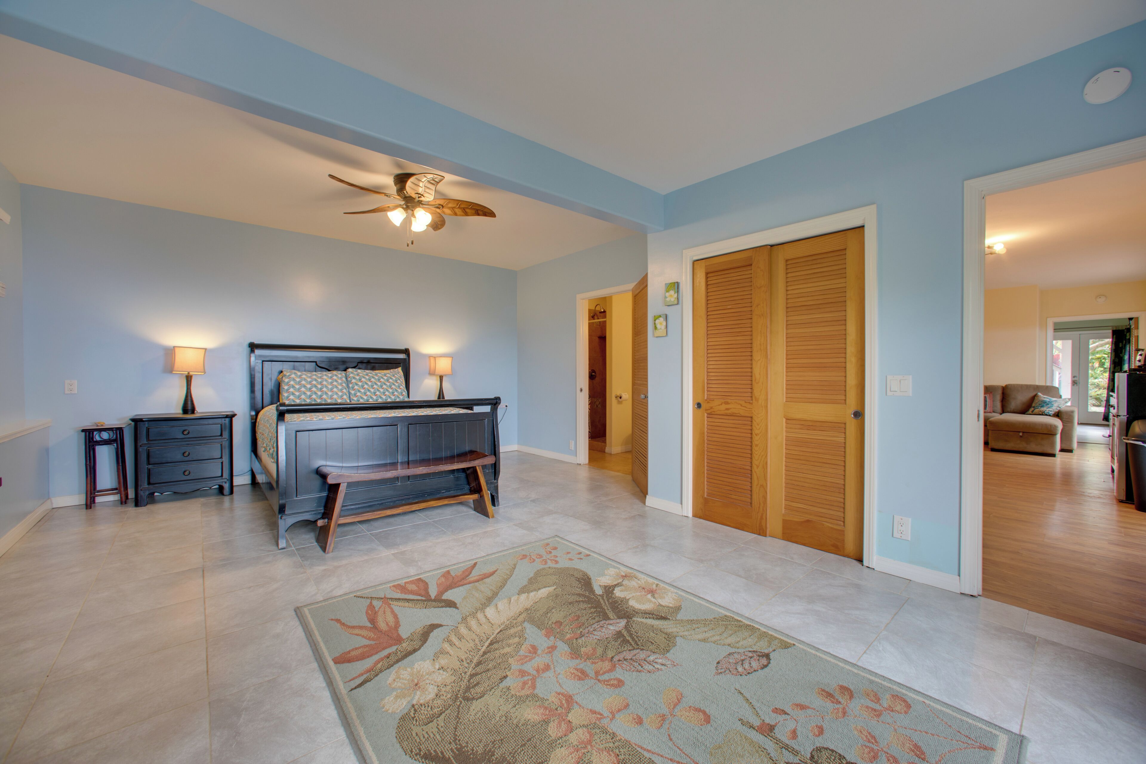 A bedroom with a bed, bedside tables, a ceiling fan, and a wooden door.