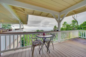 A covered outdoor deck with a white railing, a round table with chairs, and a view of the ocean. - Ocean-View Group Retreat! 8 Mi to Magic Sands (Holualoa)