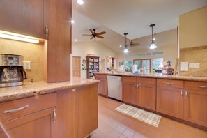 A kitchen with wooden cabinets, a dishwasher, a coffee maker, and pendant lights.