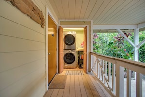 A covered wooden deck with a laundry room featuring a front-loading washer and dryer.