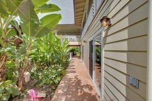 A covered outdoor area with a pathway, plants, and a building with a balcony.