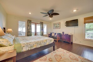 A bedroom with a bed, a desk, a chair, a television, and a ceiling fan.