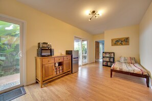 A spacious room with a wooden bed, a kitchenette with a microwave, and a bookshelf.