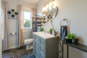 Un baño con inodoro, lavabo y espejo, además de un perchero para toallas.