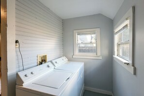 A laundry room with a white washing machine, a dryer, and a window.