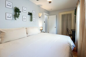 A bedroom with a large bed, a bedside lamp, and motivational wall art.