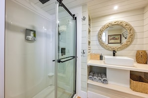 Un bagno moderno con cabina doccia in vetro, un lavandino bianco e uno specchio decorativo con cornice elaborata.