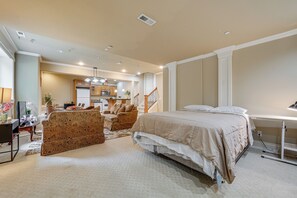 Een slaapkamer met een bed, een bureau en een stoel. Een trap leidt naar een andere kamer.