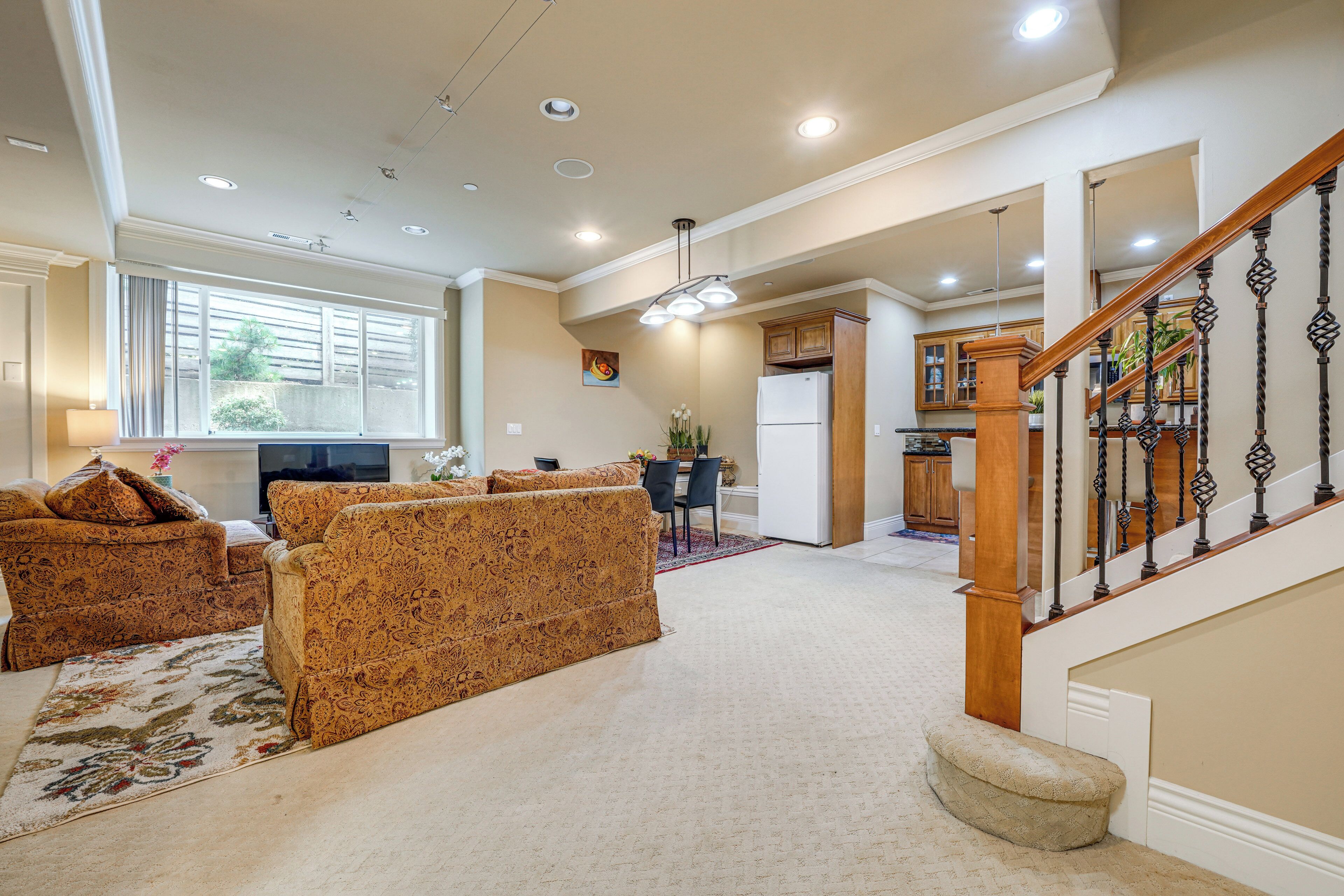 A spacious living area with a sofa set, a dining table, and a kitchen in the background.