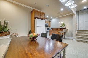 Een eetruimte met een houten tafel, stoelen en een schaal met fruit.