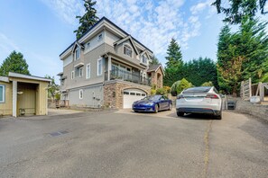 Een tweelaags huis met een garage, een oprit en twee auto's op de oprit.