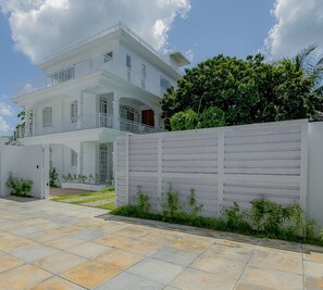 A two-story building with a balcony, a gated entrance, and a paved driveway. - The Colonial House I (Grand Baie)