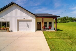 A single-story building with a garage, a covered porch with two chairs, and a well-maintained lawn. - Near Parks & Dtwn Clarinda! 'House of Stroburg' (Clarinda)