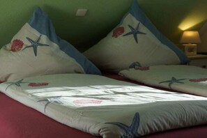 A bed with pillows featuring starfish and seashells. - Boatswain's Residence (Norddeich)