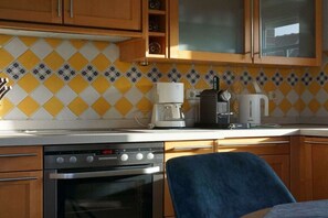 Een keuken met een fornuis, koffiezetapparaat en kastjes.