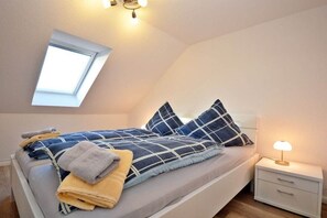 Ein Schlafzimmer mit einem Bett, einem Nachttisch, einer Lampe, einem Fenster und einer Deckenleuchte.