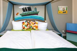 Ein Bett mit Baldachin, Kissen und einem Wandgemälde eines Schiffes.