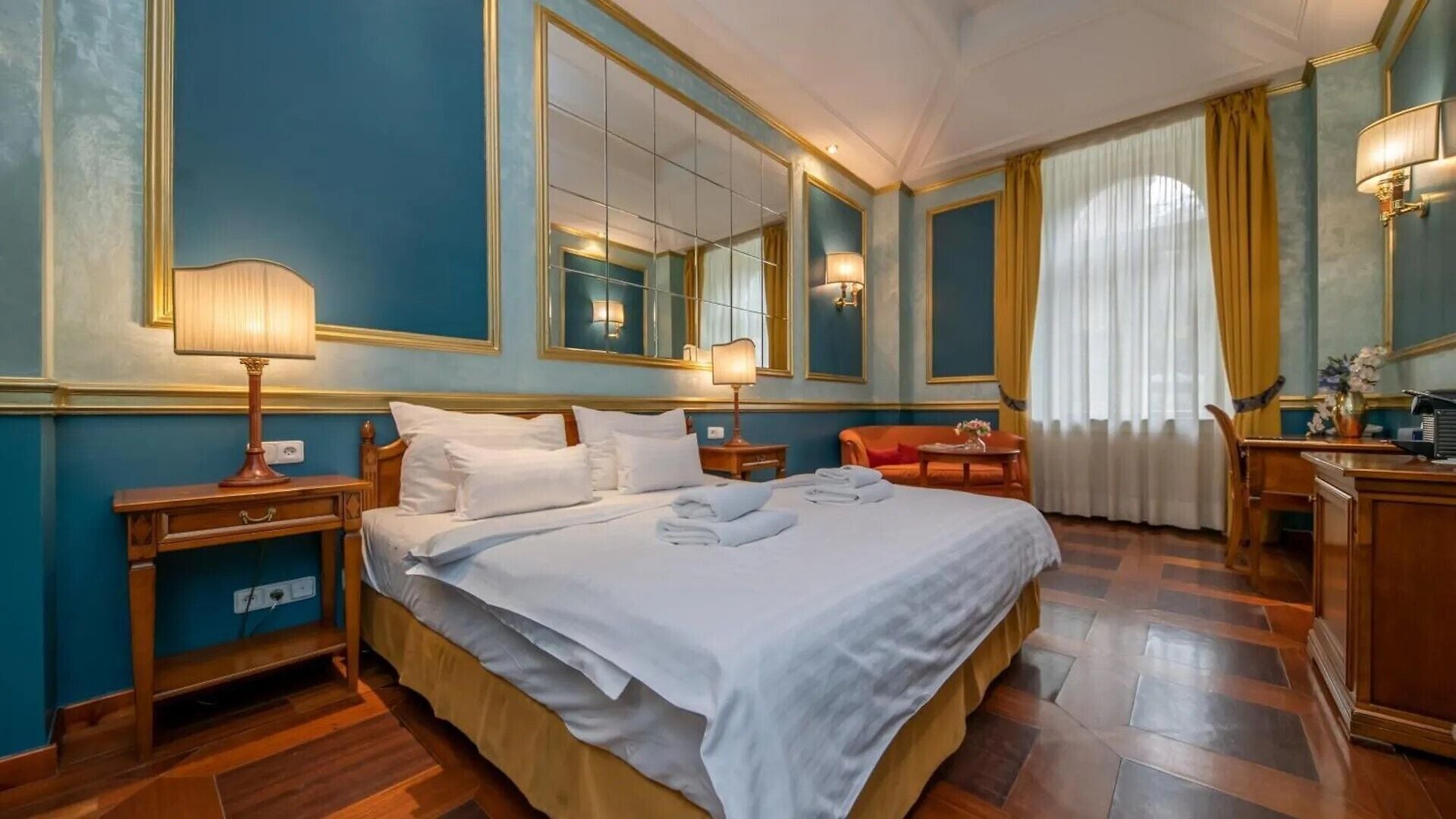 Une chambre d’hôtel avec un grand lit, des tables de chevet, un bureau, une chaise et un miroir.