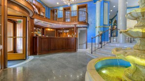 A lobby with a reception desk, a staircase, and a fountain. - Kinsky Fountain (Hlavní město Praha)