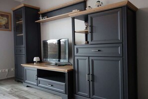 A dark-colored entertainment unit with a television, shelves, and drawers. - in the house Stranddüne, No. 14 (Haffkrug)