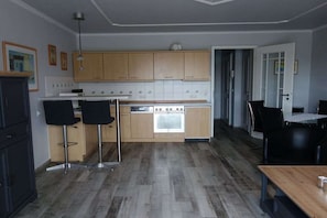 Eine moderne Küche mit Holzschränken, einem eingebauten Backofen und zwei Barhocker.
