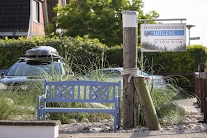 A wooden post with a sign for 'Ferienwohnungen Lütgens' and a blue bench in front. - Holiday apartment with 1 bedroom (Travemünde)