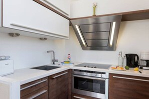 A modern kitchen with a built-in oven, a stovetop, and a sink. - Villa Agnes Apartment 11 (Binz)
