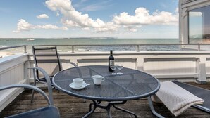 A round metal table with two white cups and a bottle, set on a wooden deck overlooking the sea. - Villa Agnes Apartment 11 (Binz)