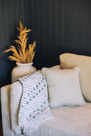 Ein Sofa mit weißer Decke und einer Vase mit Trockenpflanzen.