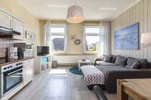 Ein kompakter Wohnbereich mit Küchenzeile, Schlafsofa, Fernseher und Essecke.