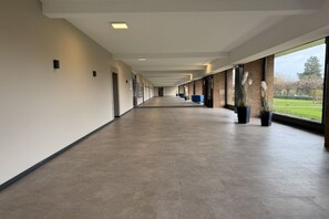 A long corridor with a tiled floor, large windows, and potted plants. - Holiday apartment with 1 bedroom (Travemünde)