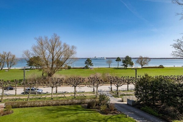 A park with a pathway, trees, and a view of the water. - Holiday apartment with 1 bedroom (Travemünde)