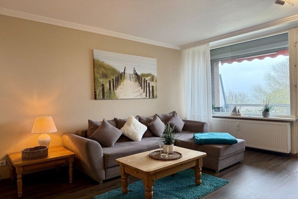 Uma sala de estar com sofá, mesa de centro, luminária e um quadro na parede.