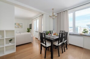 A modern dining area with a black table and chairs, a chandelier, and large windows with curtains. - Lumina 2room Apart with Balcony 6 guests (Warszawa)