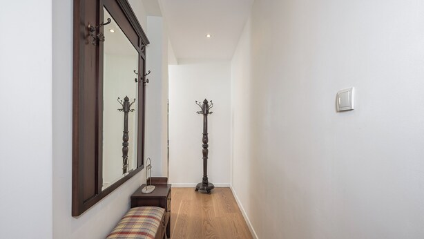 Un passadís amb una banca, un penjallum i una làmpada de terra.